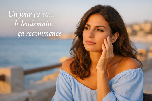 Femme méditerranéenne en bord de mer touchant sa joue avec une expression pensive, illustrant une peau qui pèle par moments avec lumière naturelle douce
