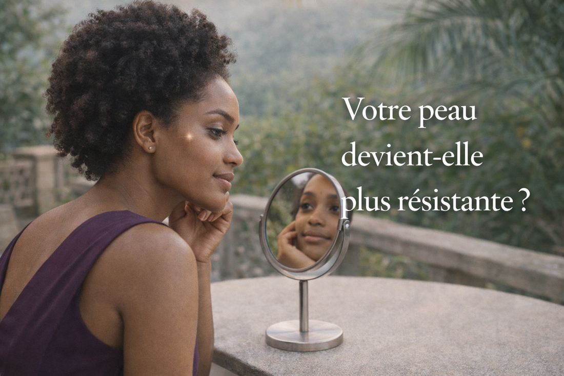 femme africaine robe prune observant sa peau dans un miroir peau plus resistante evolution naturelle de la peau