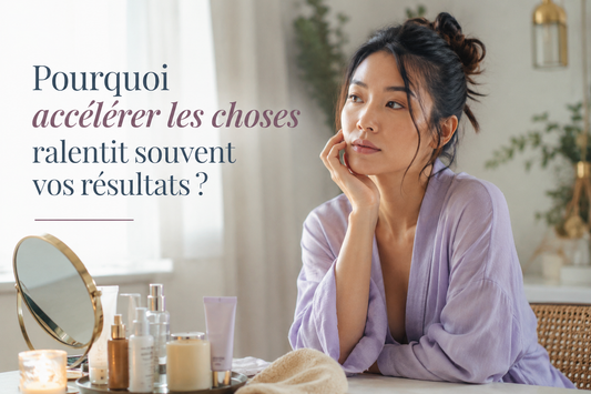Femme asiatique en peignoir lilas observant sa peau dans une ambiance lumineuse et apaisante illustrant la surcharge des routines beauté et le rythme biologique de la peau.