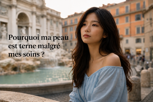 Femme asiatique au teint terne observant son visage devant la fontaine de Trevi, illustrant pourquoi la peau peut manquer d'éclat malgré une routine de soins régulière.
